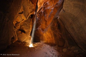 A narrow beam of light penetrates deep into the narrows of Buckskin Gulch and gently illuminates the side walls of the canyon.