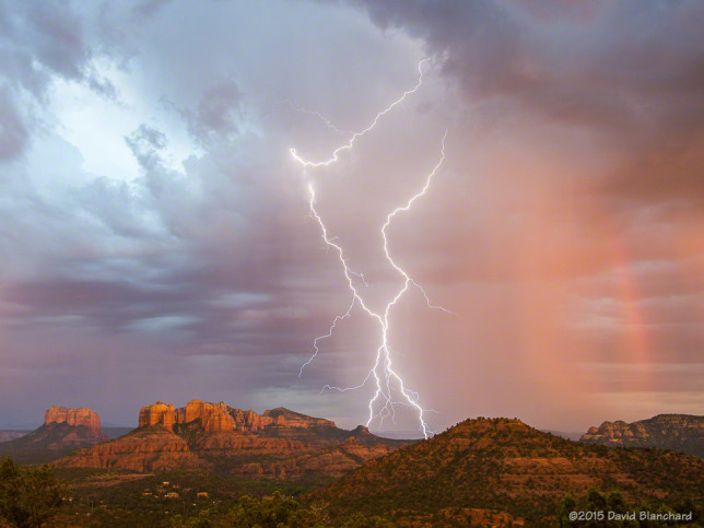Lightning and a partial rainbow frame Cathedral Rock in Sedona, Arizona.