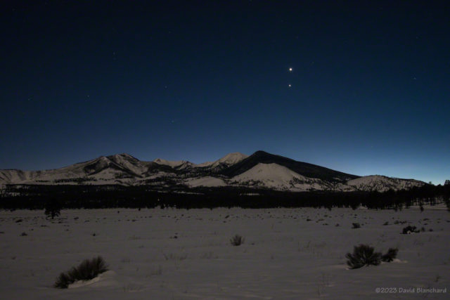 Venus and Jupiter in the evening twilight sky. A waxing Moon illuminated both the foreground meadow and the peaks in the distance.