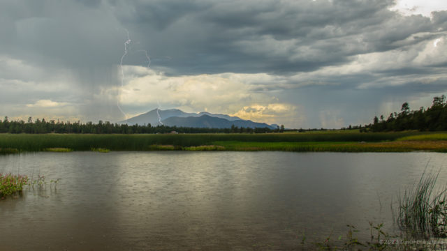 Lightning over the San Francisco Peaks with Marshall Lake in the foreground.