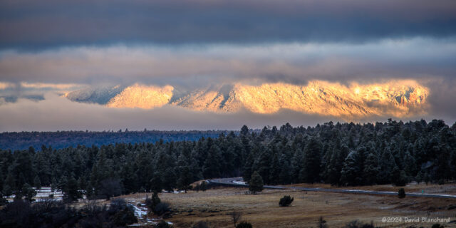Low clouds and fog partially obscure the San Francisco Peaks as the sun rises (24 Jan 2024).